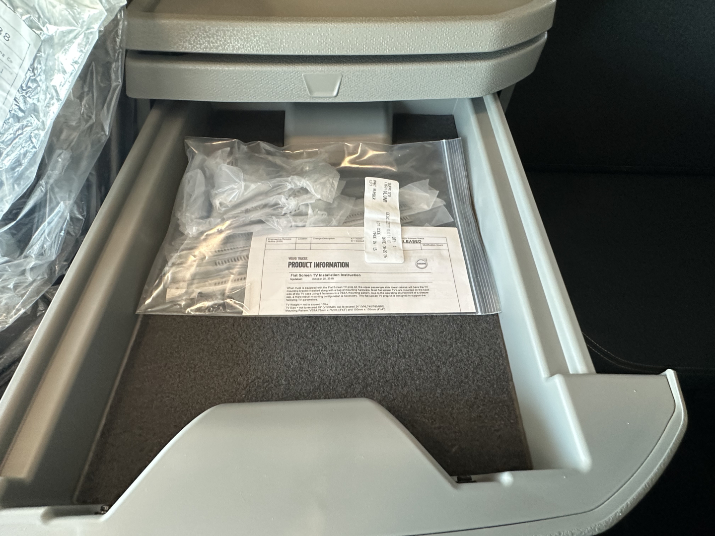 Storage tray open in Volvo VNL64T860 cab showing documents and bag inside center console.