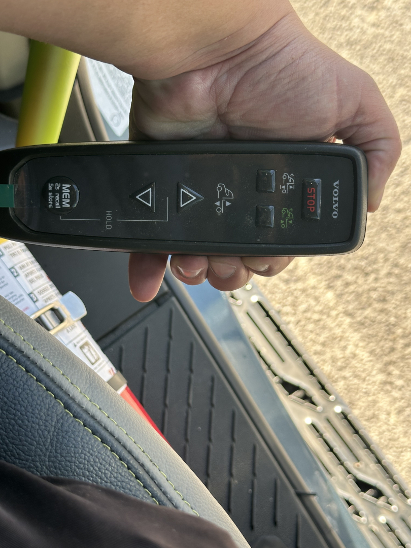 Volvo remote key fob in hand inside Volvo VNL64T860 cab showing start/stop button and lock/unlock icons.