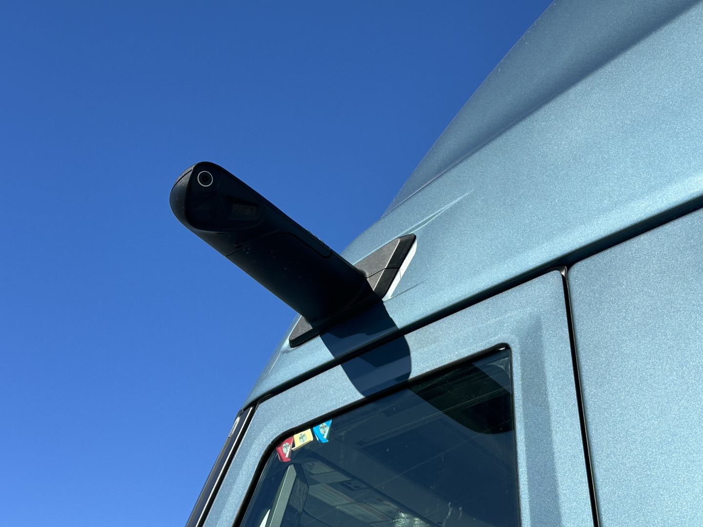 Volvo VNL64T860 sleeper truck corner showing roof antenna and window.