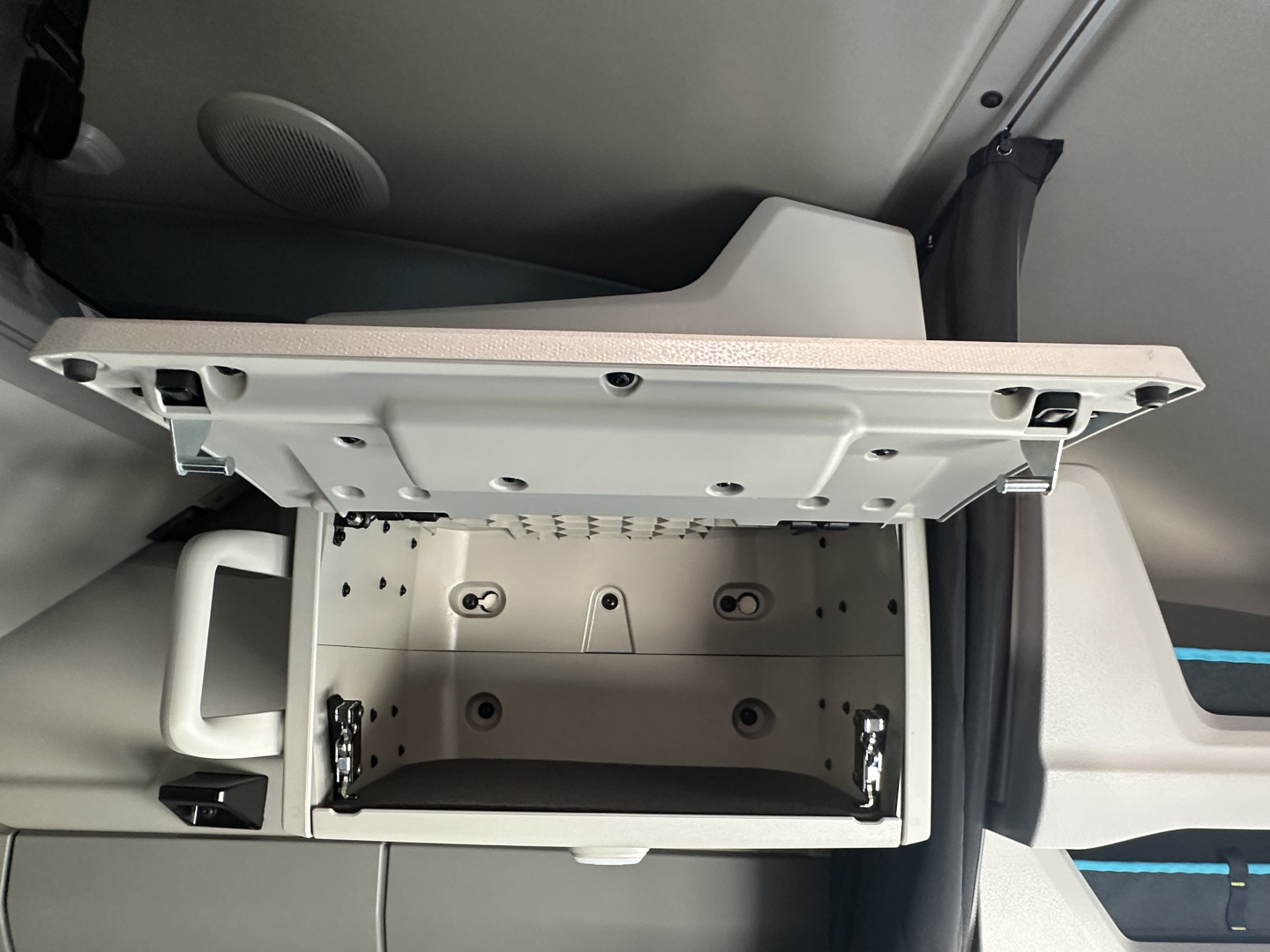 Cabin storage drawer open in a Volvo VNL64T860 sleeper cab showing interior of the shallow overhead compartment.