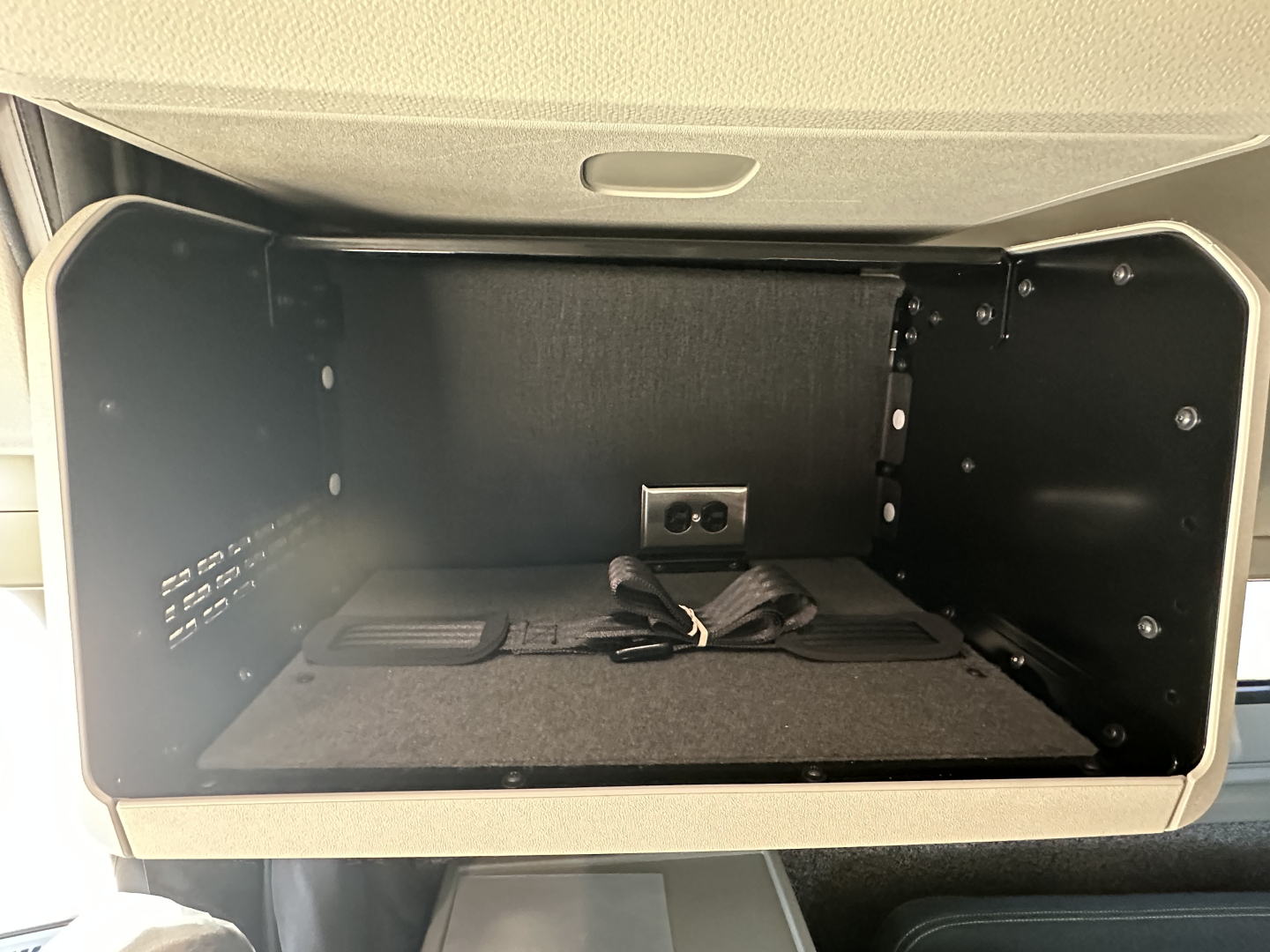  Volvo VNL64T860 sleeper cab storage compartment interior with power outlet and wiring harness.