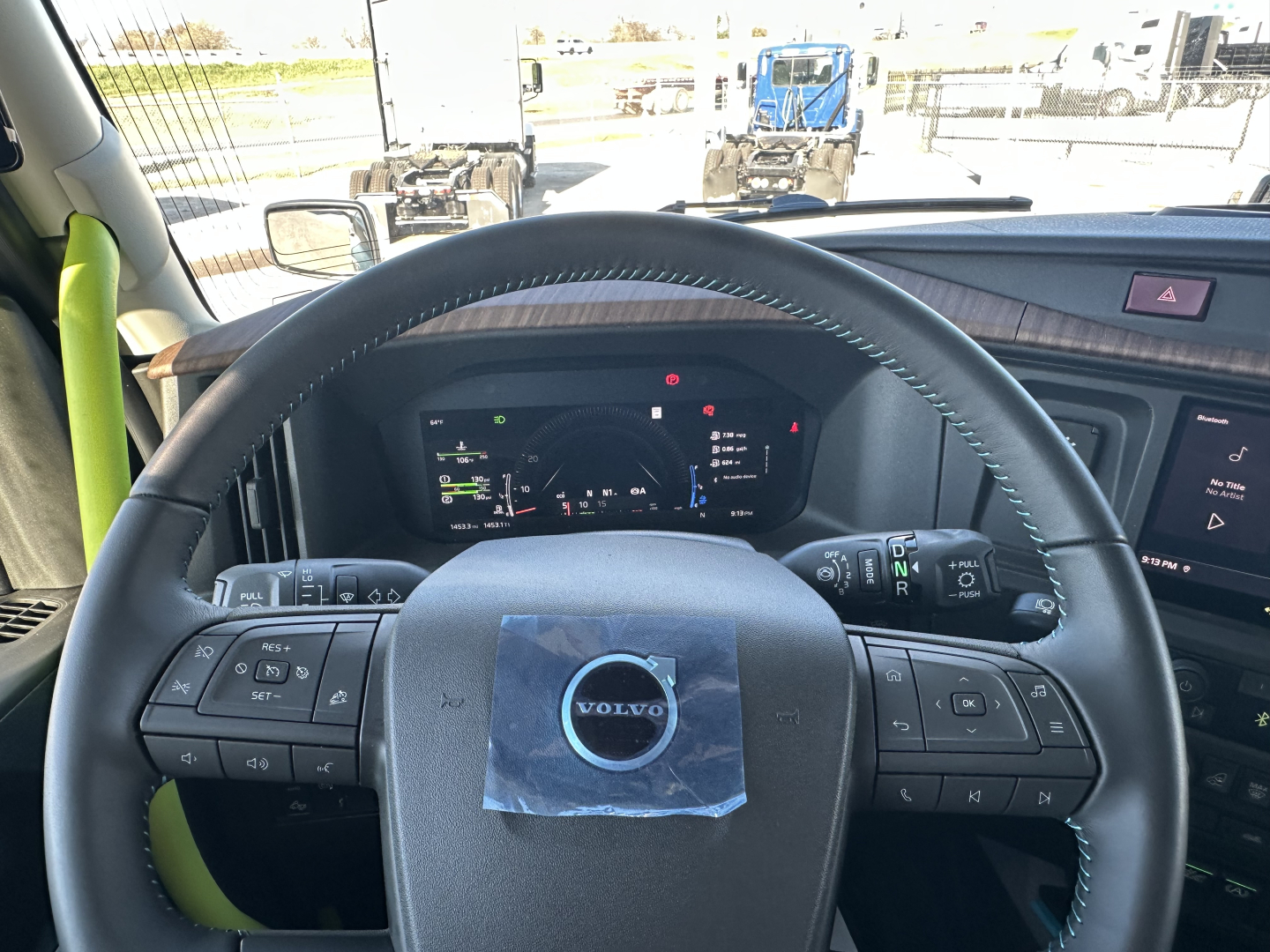 Volvo truck cabin steering wheel with dashboard controls and digital gauge cluster visible.