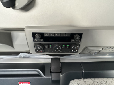 Dashboard control panel of a Volvo truck interior showing climate controls and media buttons.