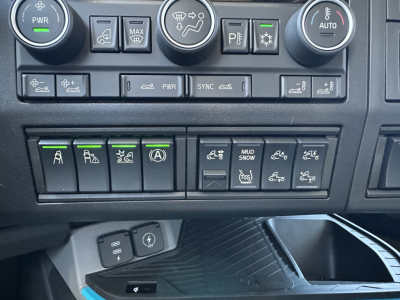 Volvo VNL dash panel showing multiple switches with green indicators and circular climate controls visible.