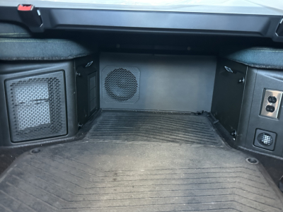 Volvo VNL64T860 cab area showing storage compartments and speaker, interior rear cabin floor with rubber matting.