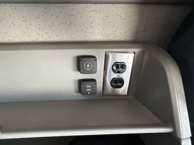 Volvo VNL64T860 interior close-up showing 12V power outlet, USB-C/aux ports, and dual 120V AC outlets in dash area.