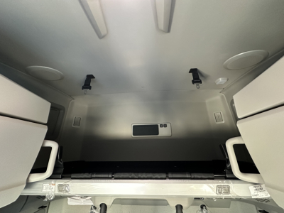  Volvo VNL64T860 sleeper cab interior storage area with overhead shelves and tie-downs, rear-view image shows metallic interior walls and a small rectangular cabinet.