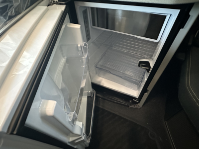  Volvo VNL64T860 sleeper cab area showing open under-counter refrigerator with empty shelves and compact interior. 