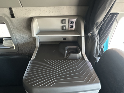 Volvo VNL64T860 sleeper cab interior showing dashboard controls and storage shelf with ribbed floor mat.