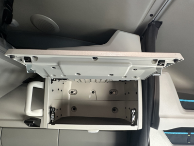 Cabin storage drawer open in a Volvo VNL64T860 sleeper cab showing interior of the shallow overhead compartment.