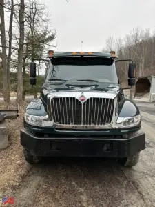 Front view of a green 2018 International 4400SBA dump truck showing chrome grille, bumper, and large mirrors.