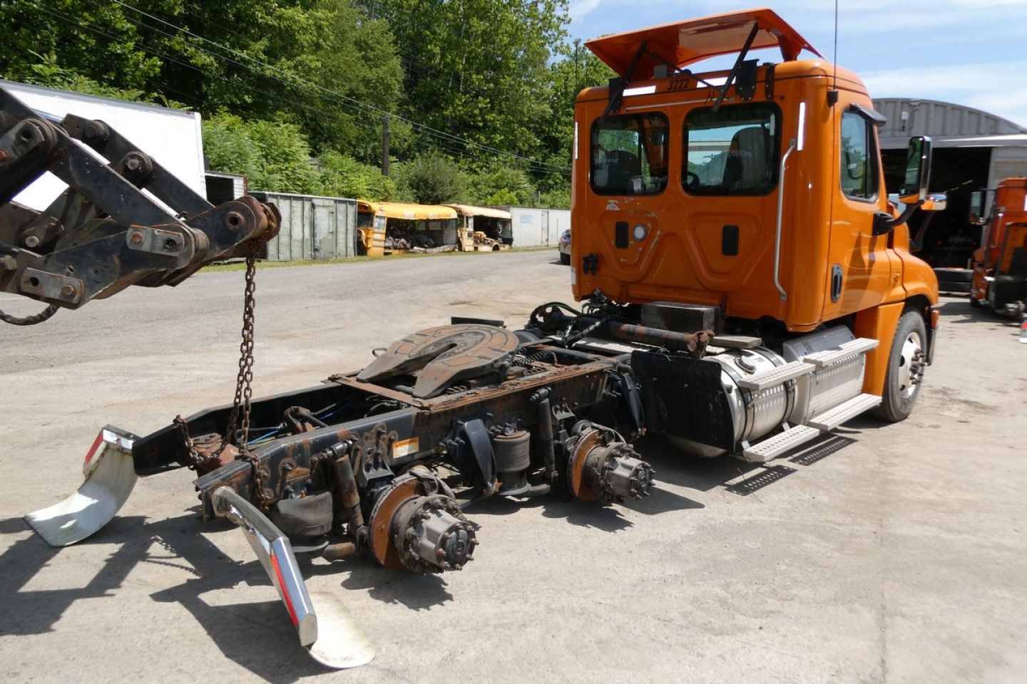 Freightliner Cascadia 125 truck chassis with orange cab, exposed drivetrain and suspension components.