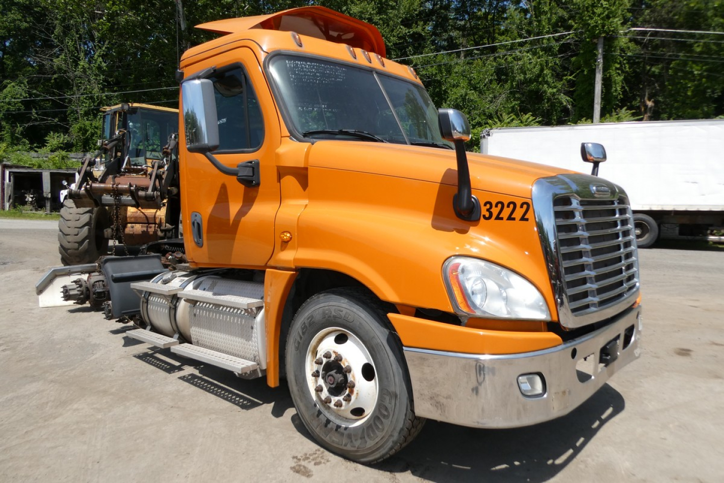 Orange Freightliner Cascadia 125 daycab cab exterior with black grille and side steps, number 3222 on fender, front view.