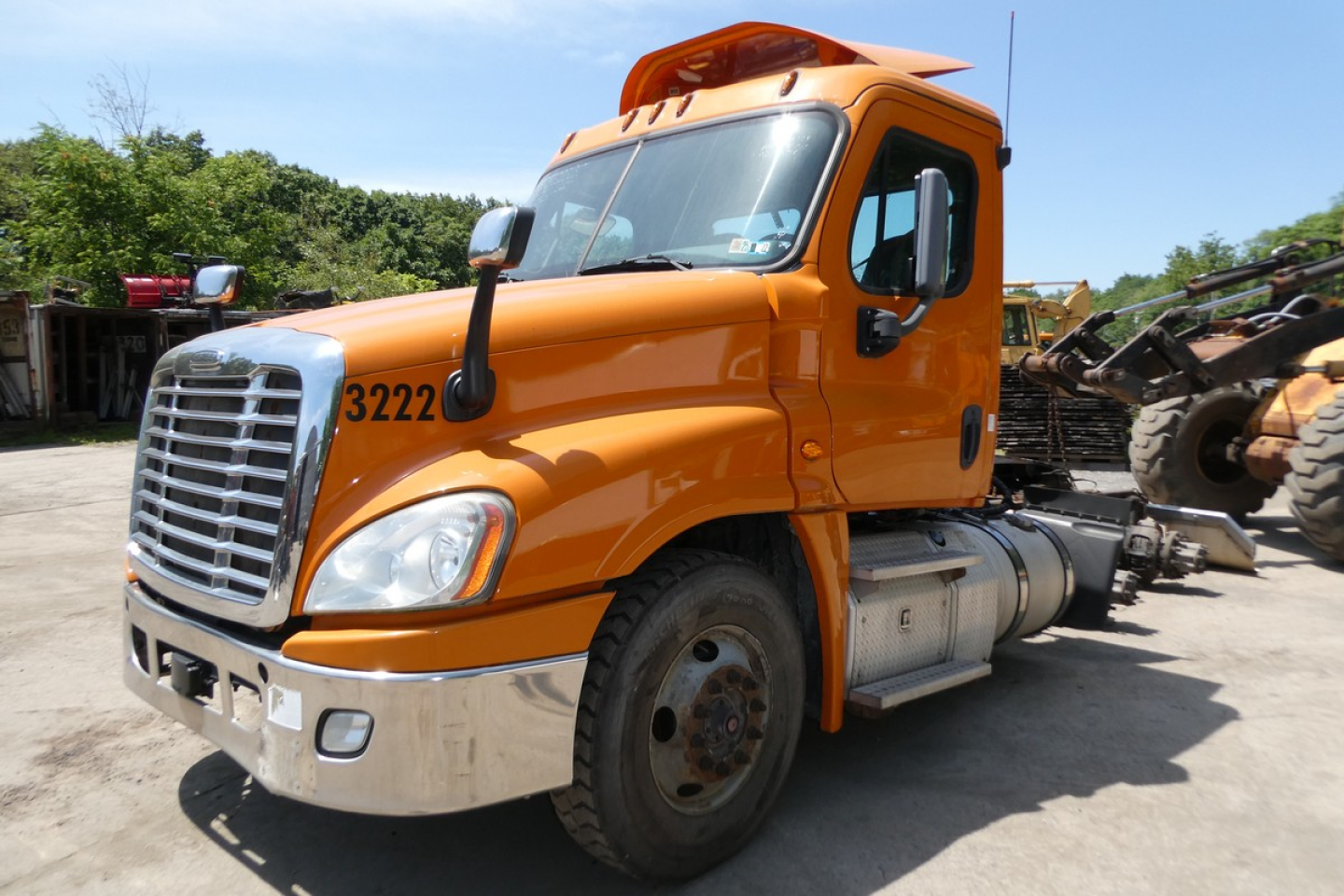 Truck cab showing orange Freightliner Cascadia 125 front-left view with grille, headlight, and number 3222 on fender.