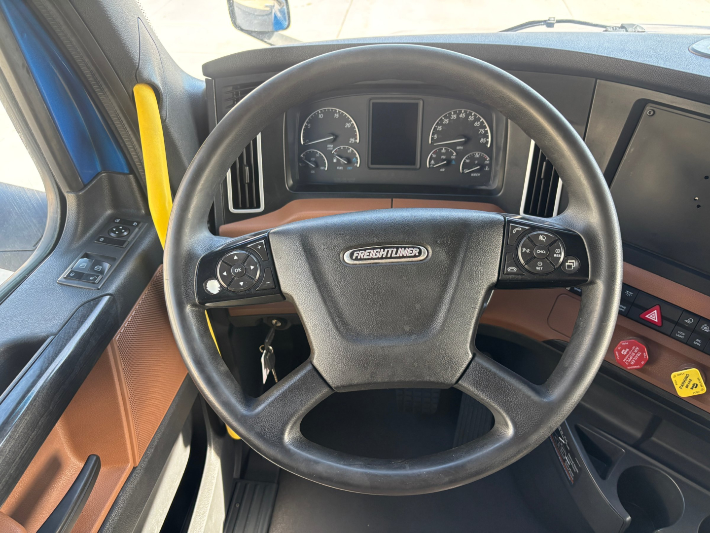 Steering wheel and dashboard of Freightliner PT126064ST semi truck cab; center shows Freightliner badge, gauge cluster and control panels on both sides.