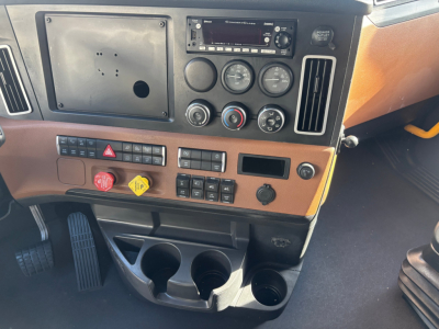 Dashboard of a Freightliner truck showing instrument cluster, control switches, cup holders, and a radio/navigation panel. Visible text includes 'Cross over' on stereo unit, various gauges, and control labels on the panel.