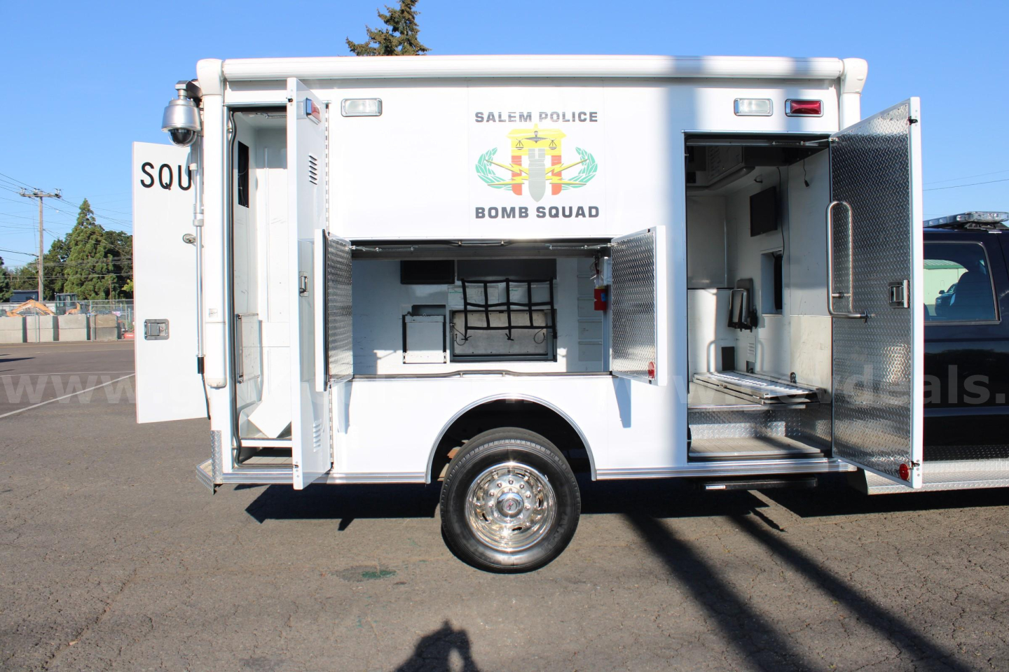 Ford F-550 cab and chassis side view with storage compartments and open rear door, showing police bomb squad markings and equipment bay.