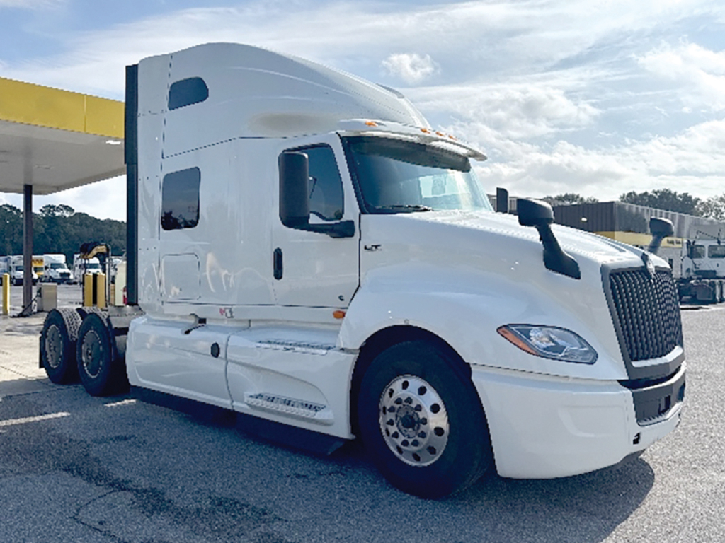 International LT Series truck cab showing large sleeper with white paint, dual rear axles, and prominent grille; front left view.