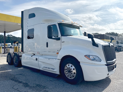 International LT Series truck cab showing large sleeper with white paint, dual rear axles, and prominent grille; front left view.