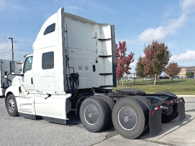 Truck tractor in white, side view showing sleeper cab and rear wheel arrangement with tandem axles.