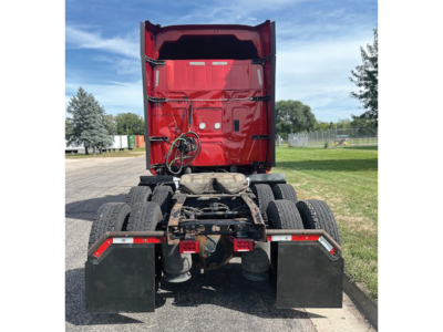 Truck rear view showing fifth wheel hitch and dual rear axles, red sleeper cab, black mud flaps, and bumper-mounted reflectors.