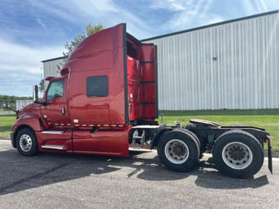 Truck side view showing a red 2020 International LT625 sleeper tractor with raised cab and dual rear axles.