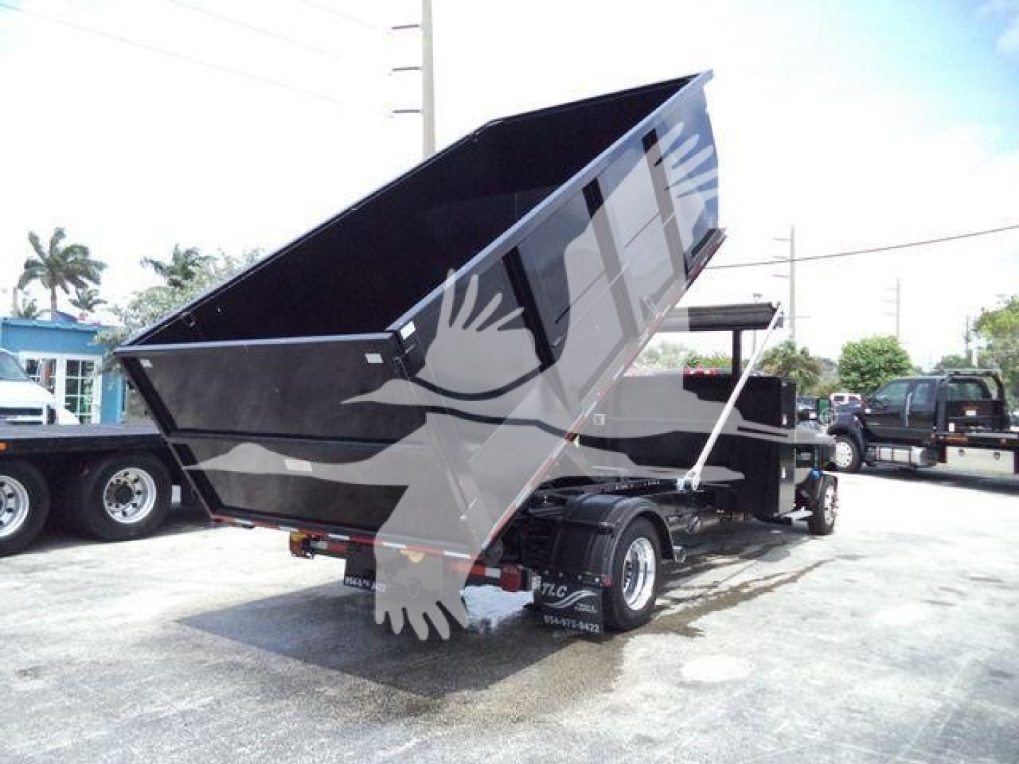 Truck bed dump trailer in raised position with dual rear wheels and black metallic finish; Chevy Silverado 6500HD label not visible; outdoor dealership lot