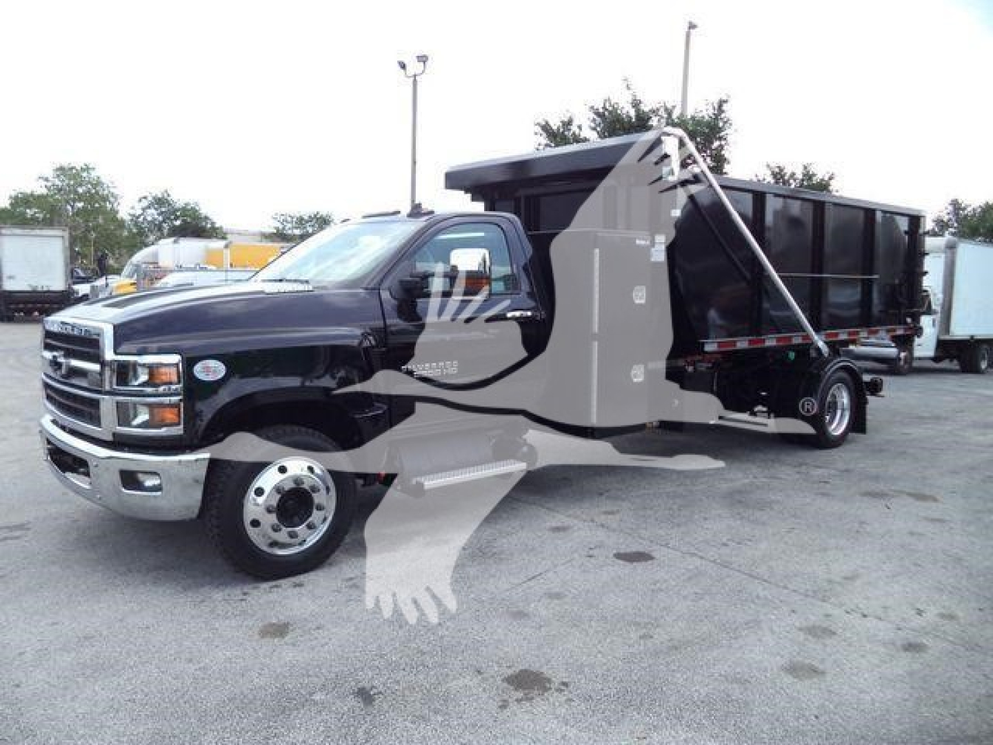 Chevrolet Silverado 6500HD dump body truck in two-tone black and tan, front grille, chrome bumper, wheel, and dumping bed visible.