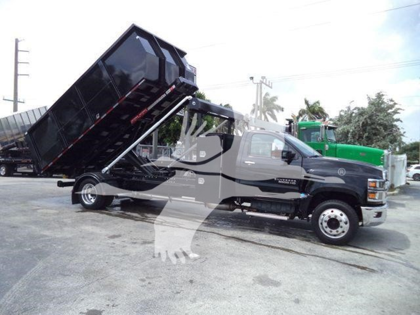 2023 Chevrolet Silverado 6500HD dump truck in service position with black dump bed raised on hydraulic piston.