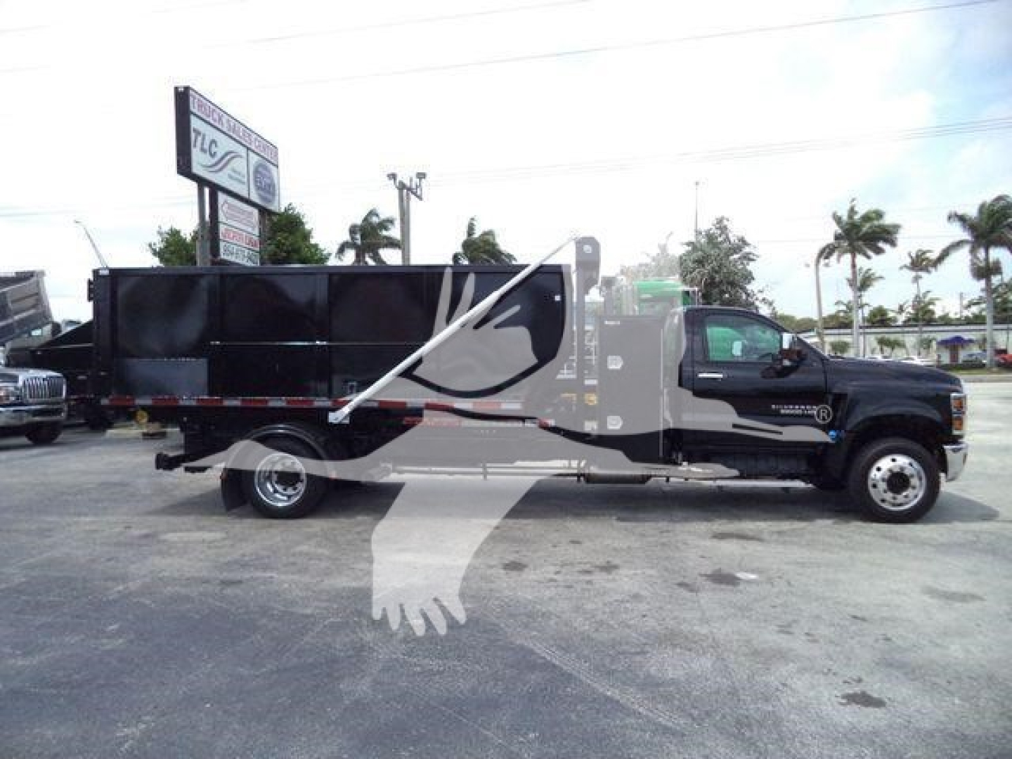 Truck side view of a black Chevrolet Silverado 6500HD dump with stock number 6500SNGTRUCK3 visible.