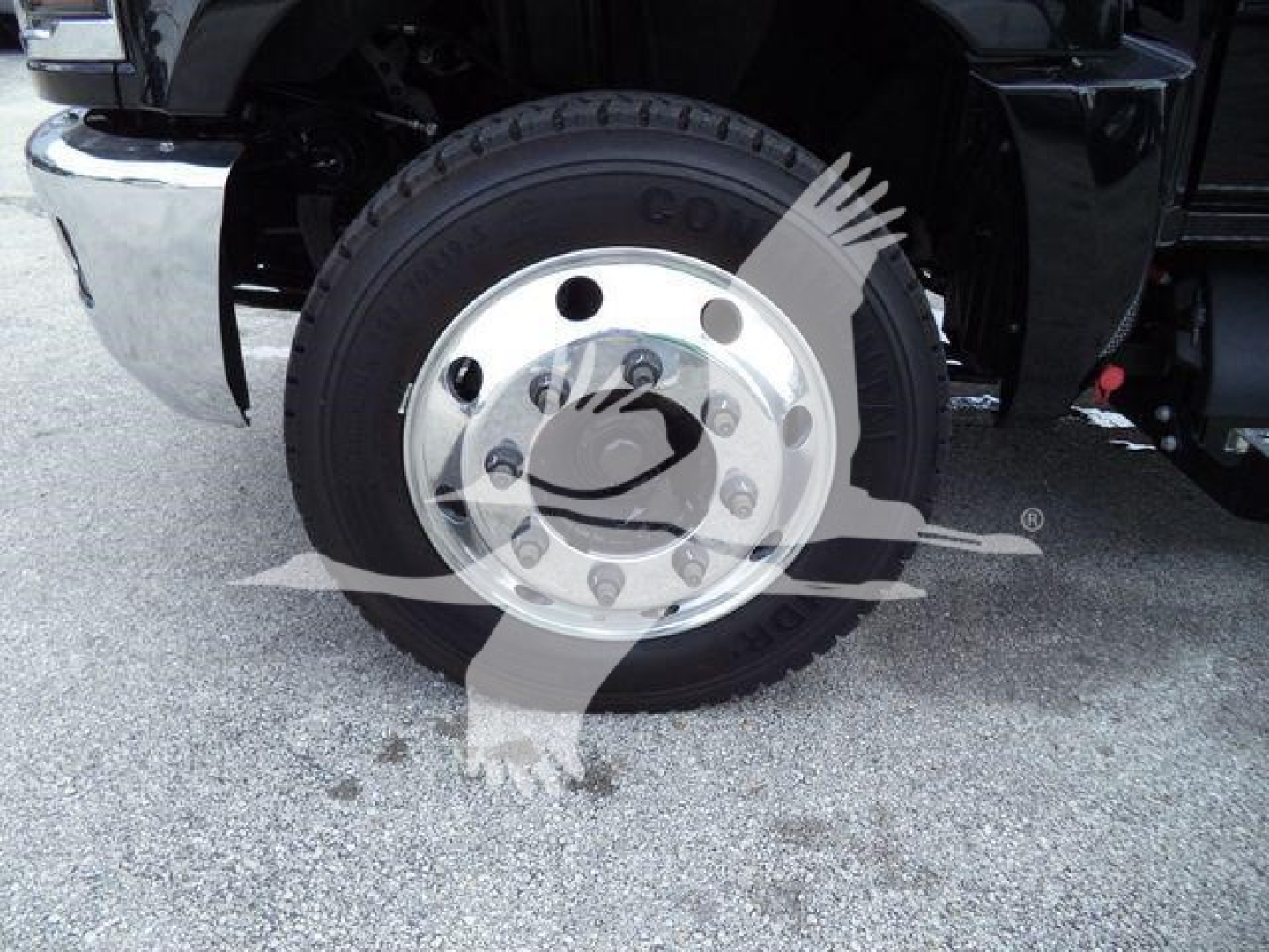 Front wheel of a Chevrolet Silverado 6500HD truck showing a Goodyear or similar tire mounted on a polished steel wheel; no legible model text visible on tire.