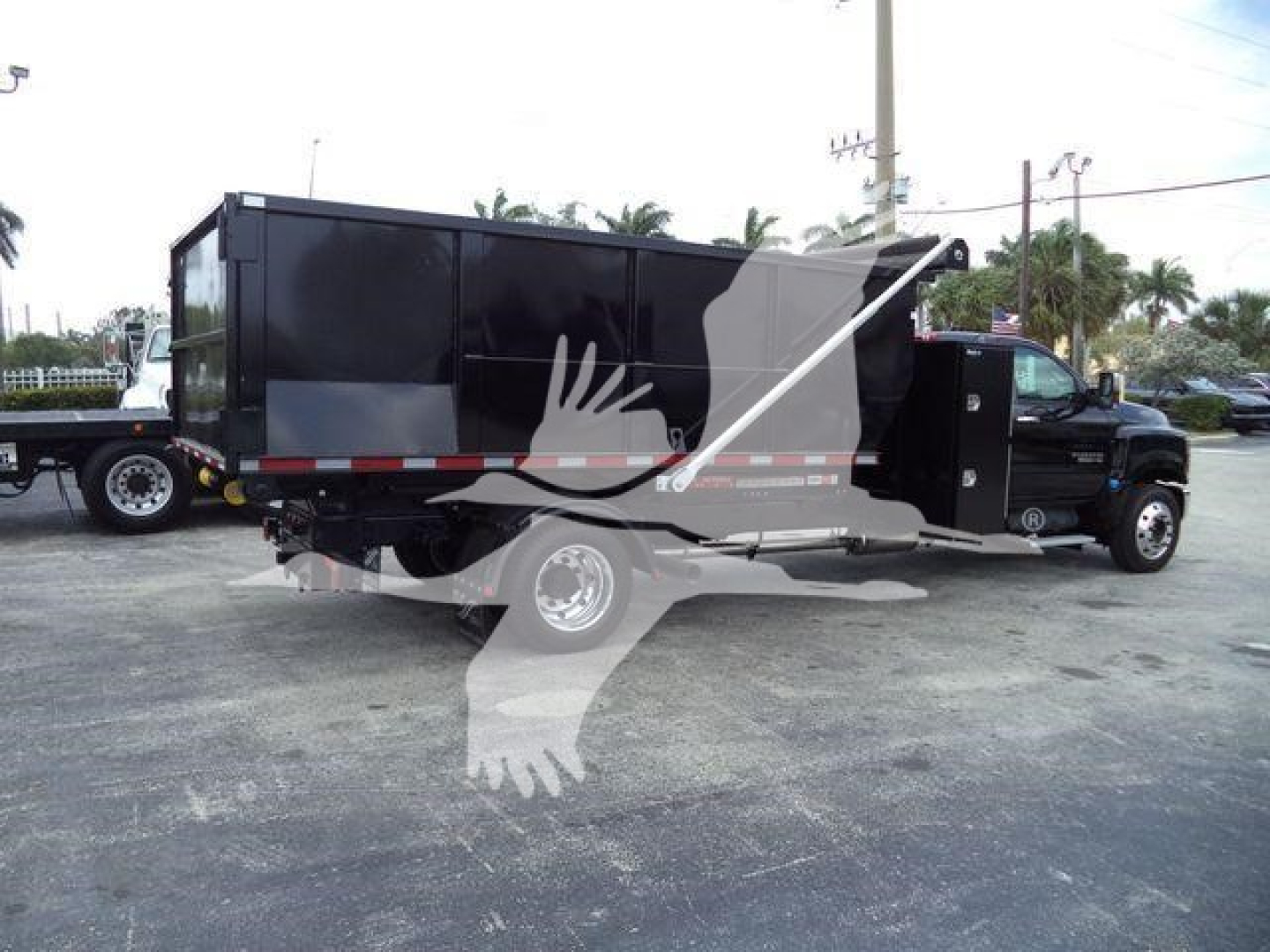 Chevrolet Silverado 6500HD truck with black dump bed, side view showing hydraulic chute and dual rear tires