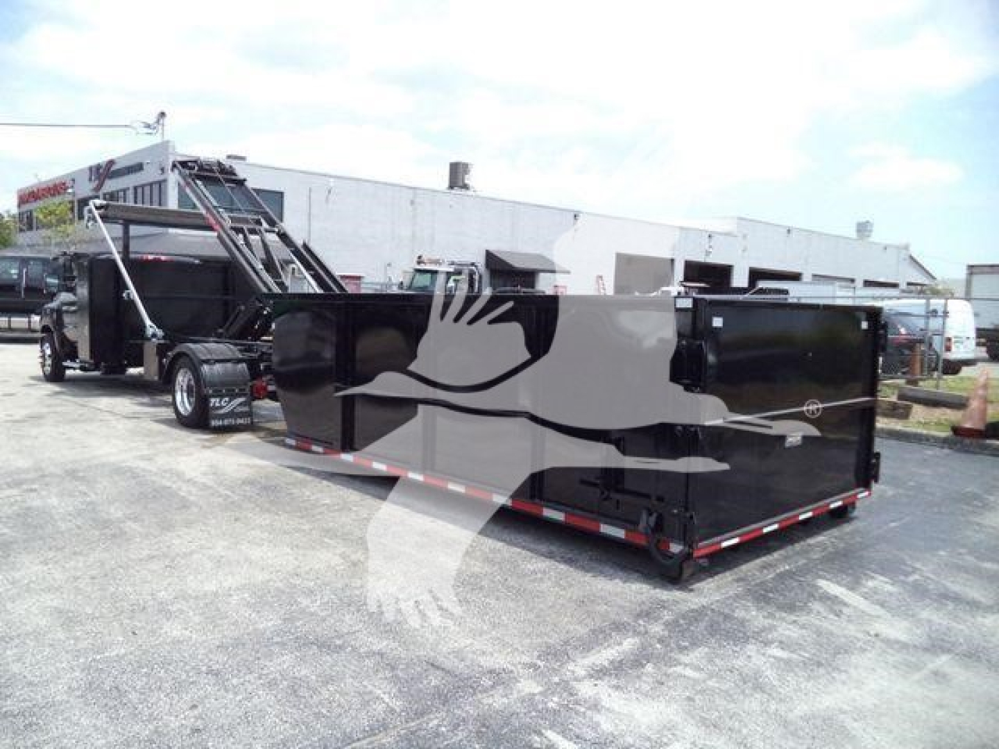 Truck bed or dump trailer attached to a Silverado 6500HD chassis, black glossy surface with red/white reflective taillines, in a lot.