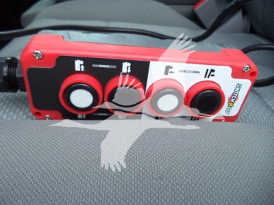 Control module with three circular ports on red and black panel, positioned on a vehicle seat.