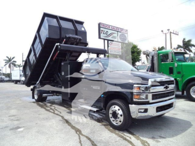 Chevrolet Silverado 6500HD dump-bed truck in a dealership lot with a raised black dump bed. Silverado badge visible on the front grille.