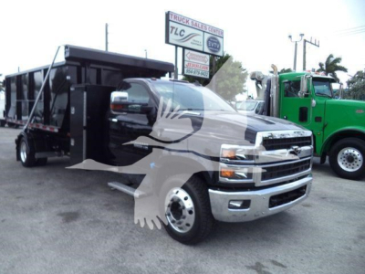 Chevrolet Silverado 6500HD dump truck in a dealership lot showing front and side view with a black dump bed and silver bumper