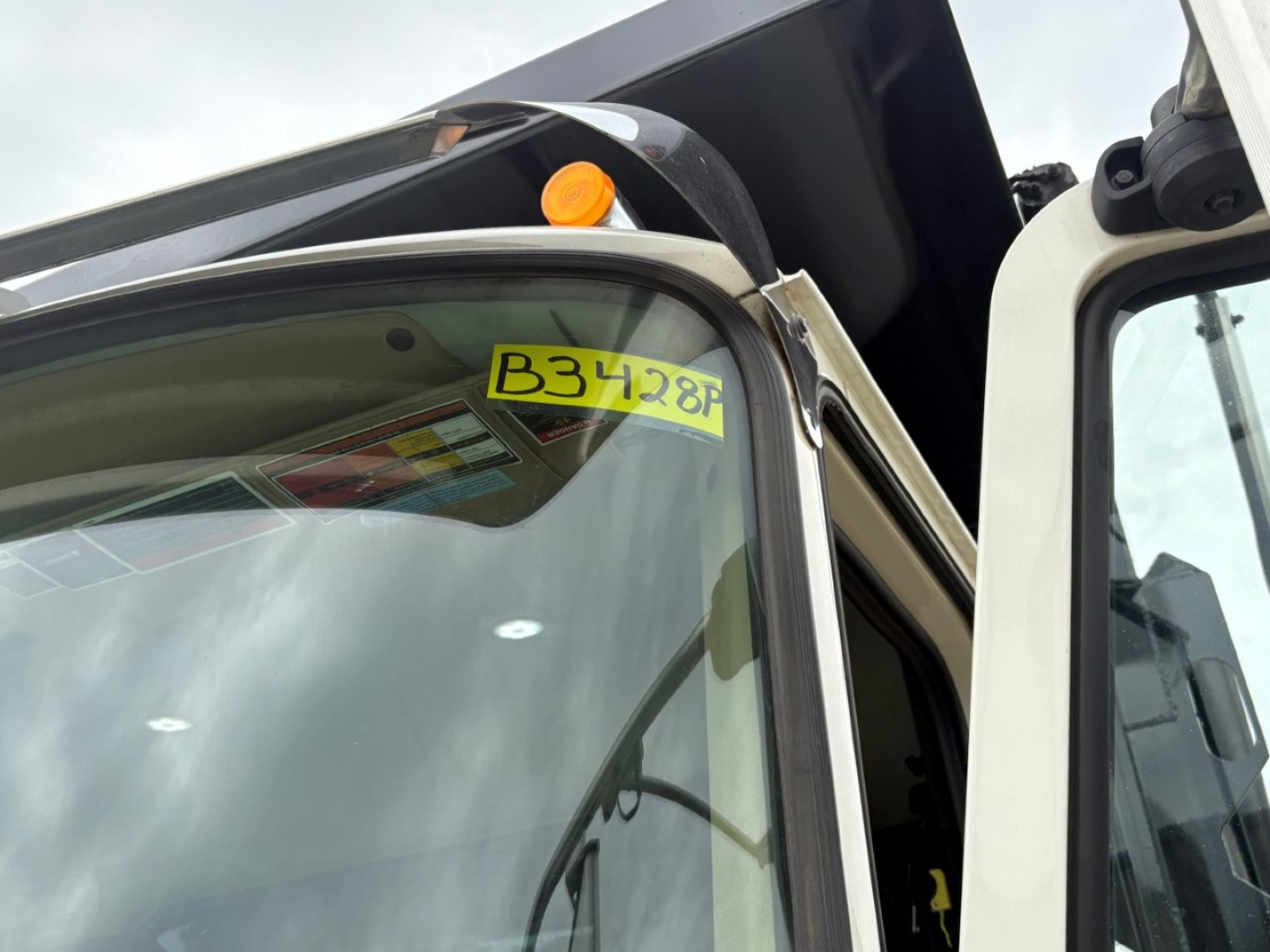 Close-up of the Mack GR64F truck cab with a yellow B3428P sticker on the window and a small orange beacon light.