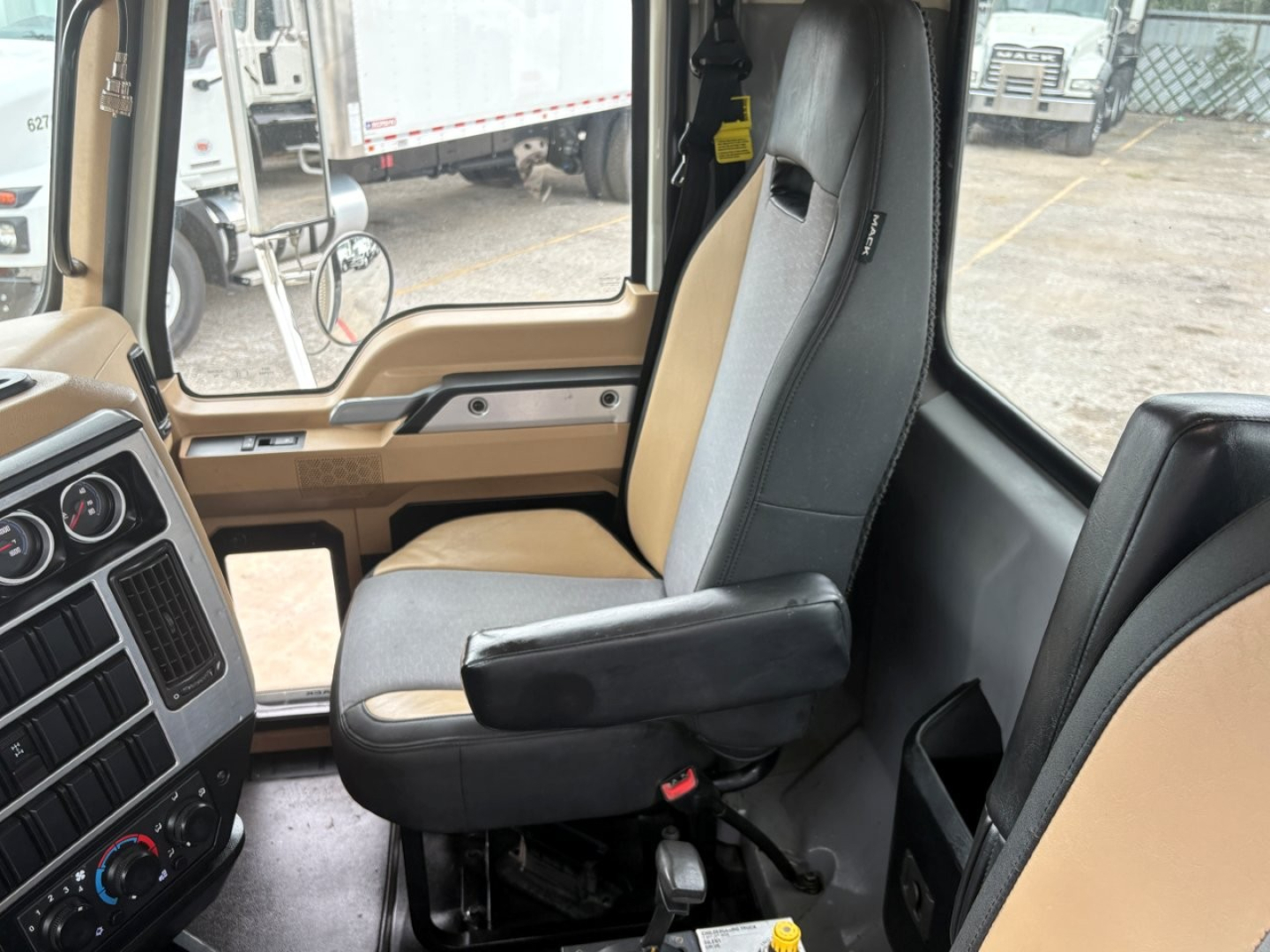 Cab interior of a 2020 Mack GR64F dump truck showing driver's seat and dashboard with beige and black upholstery.