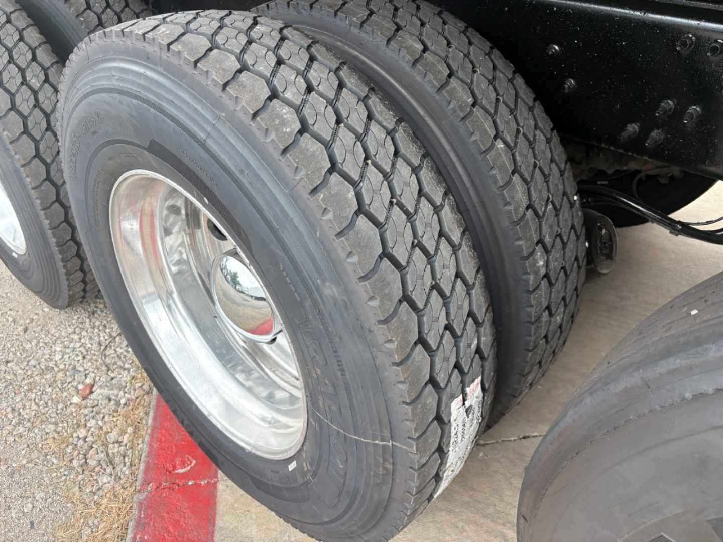 Dual rear tires on a Mack GR64F dump truck showing tread pattern and wheel hub.