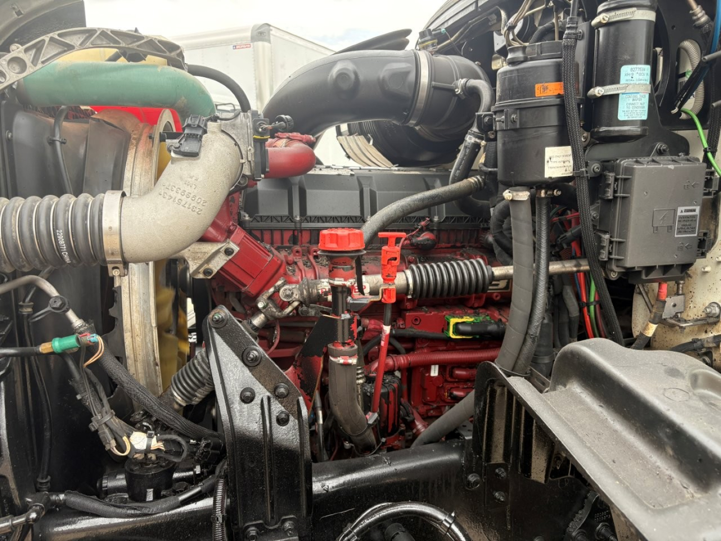 Engine bay of a 2020 Mack GR64F showing red engine block, hoses, belts, and components with surrounding black panels and wiring.