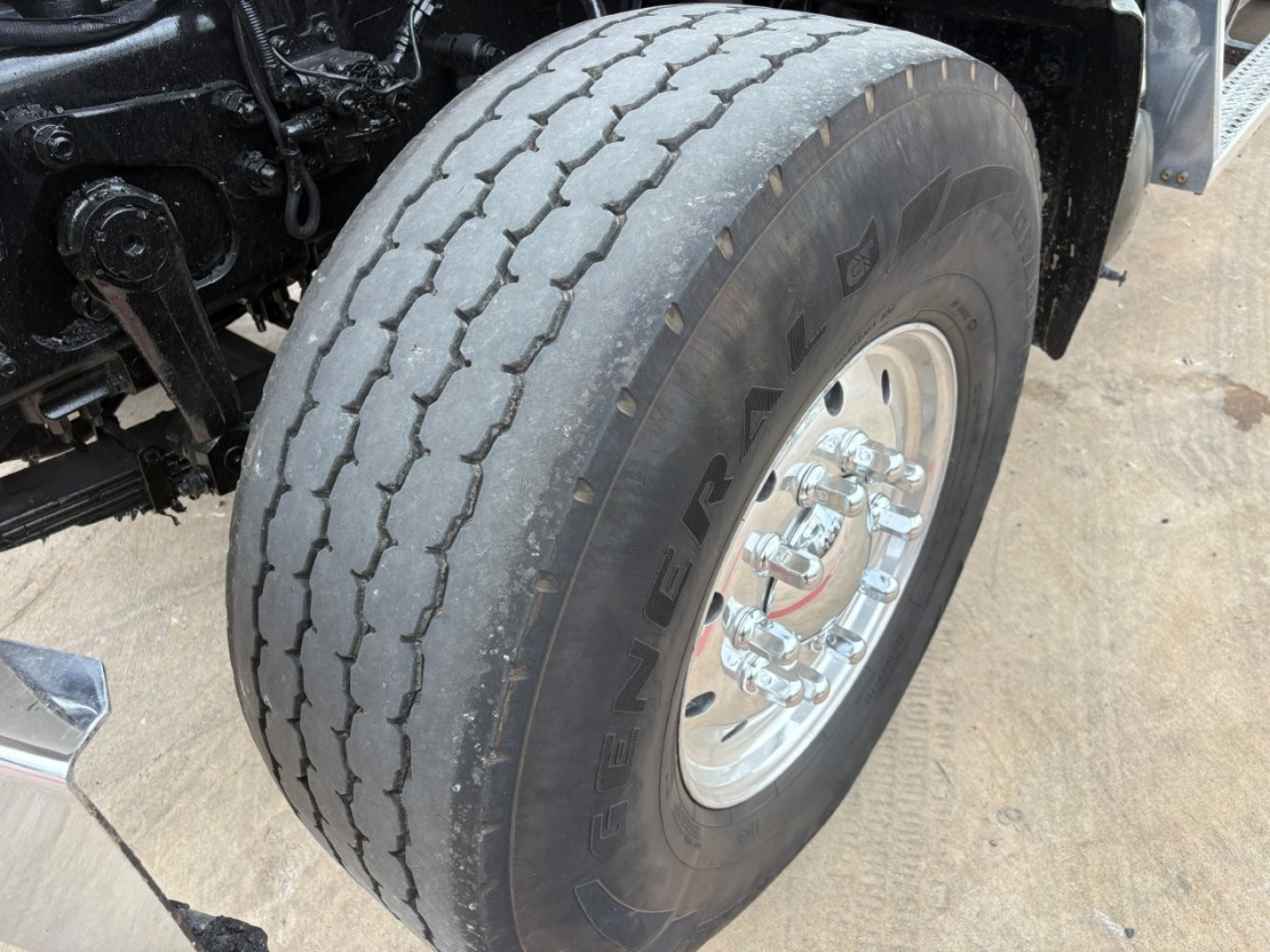 Truck wheel and tire close-up showing heavy-duty dual rear axle with Alliance wheel, curb lean and tire tread pattern.