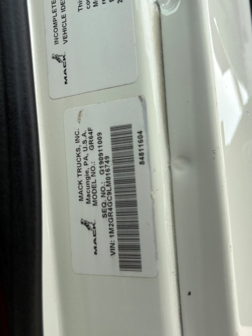 Mack Trucks VIN plate and label text on vehicle frame showing VIN 1M2GR4GC9LM016749 and stock number B3428P in a dump truck setup.