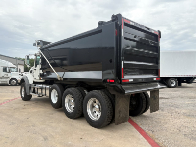 Dump truck bed of a 2020 Mack GR64F with multiple rear axles and a raised black dumping body.