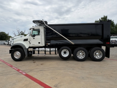 Dump truck side view showing large dump bed and Mack GR64F chassis with six wheels.