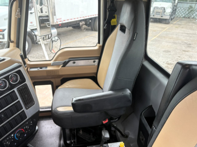 Cab interior of a 2020 Mack GR64F dump truck showing driver's seat and dashboard with beige and black upholstery.