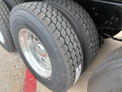 Dual rear tires on a Mack GR64F dump truck showing tread pattern and wheel hub.