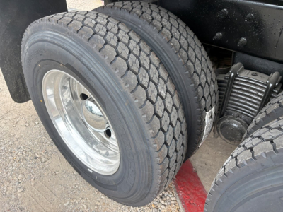 Front dual rear tire view of a Mack GR64F dump truck showing dual rear wheels and suspension components.