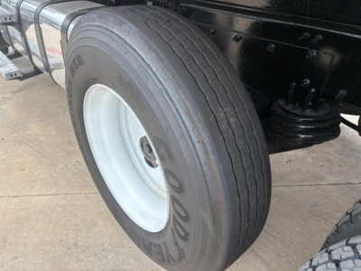 Rear wheel of a 2020 Mack GR64F dump truck showing Goodyear tire and white steel rim with black undercarriage.