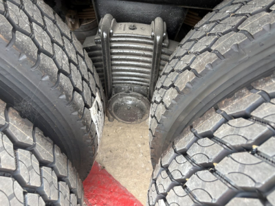 Mack GR64F drivetrain area showing tandems and suspension leaf springs between dual rear tires.