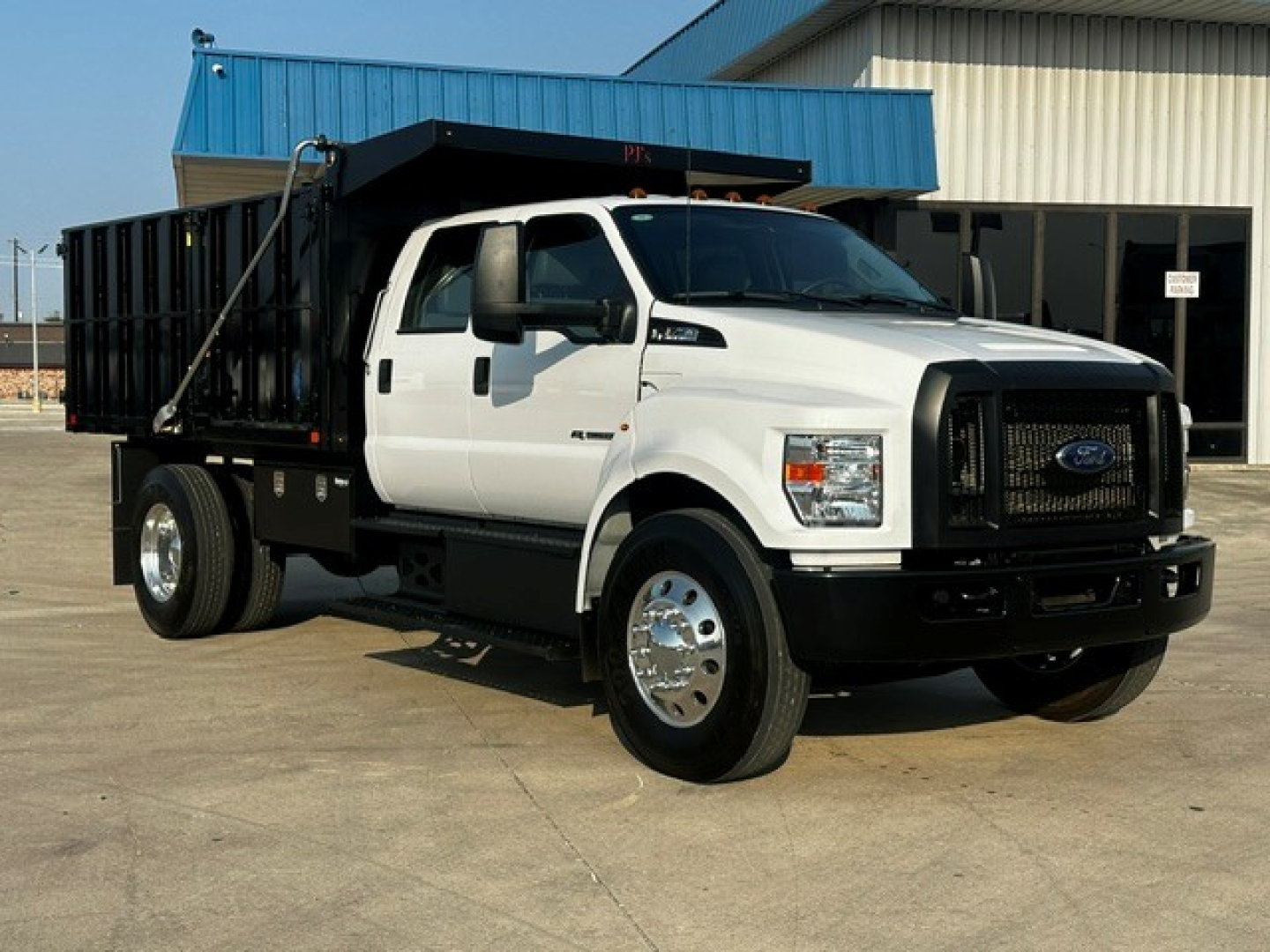 Ford F-750 dump truck in white with black grille and dump bed, front three-quarter view.
